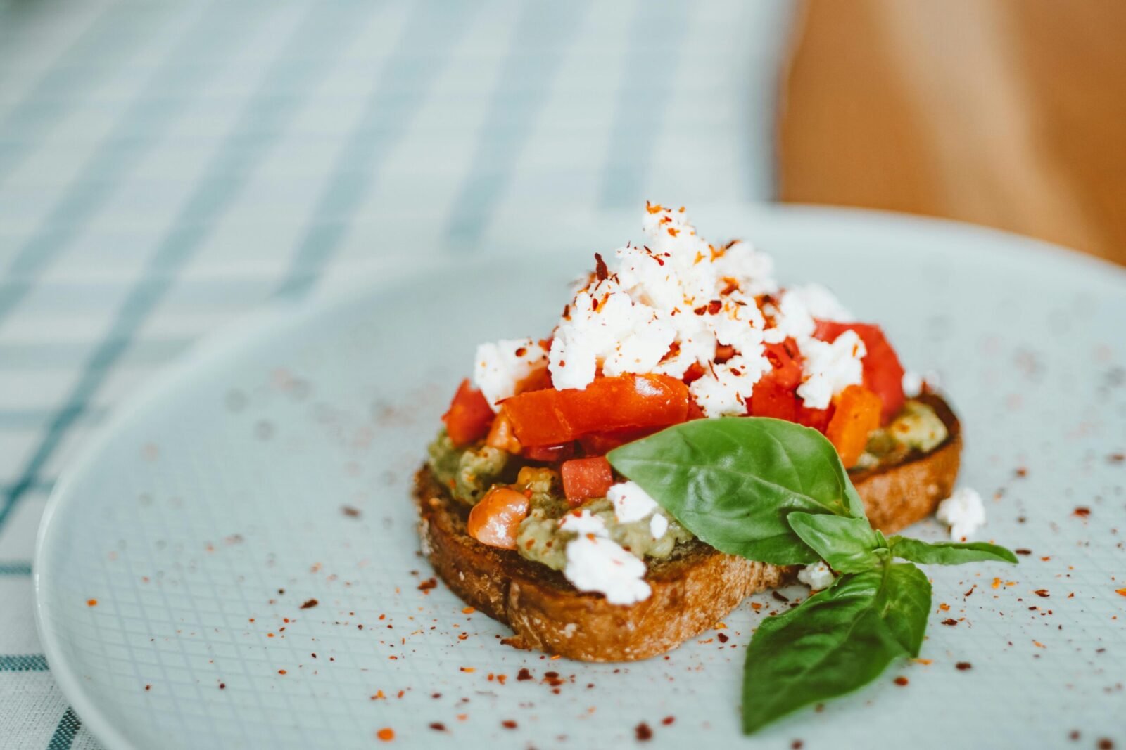 Appetizing toast with feta cheese, tomatoes, and basil leaves on a stylish plate.